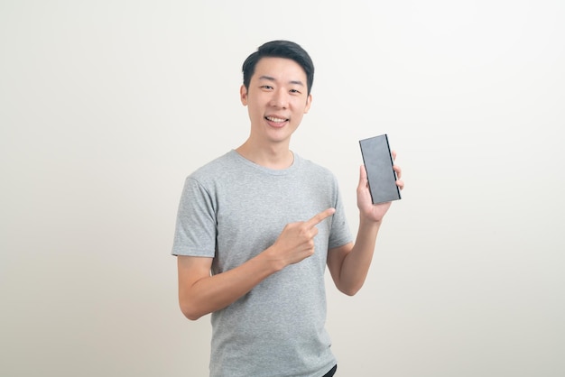 молодой азиатский человек, использующий или говорящий смартфон и мобильный телефон на белом фоне