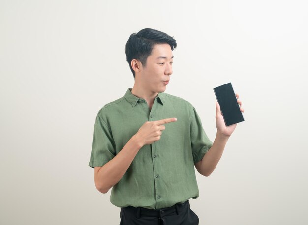 白い背景の上のスマートフォンや携帯電話を使用または話している若いアジア人男性