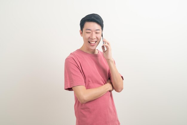 молодой азиатский человек, использующий или говорящий смартфон и мобильный телефон с счастливым лицом на белом фоне