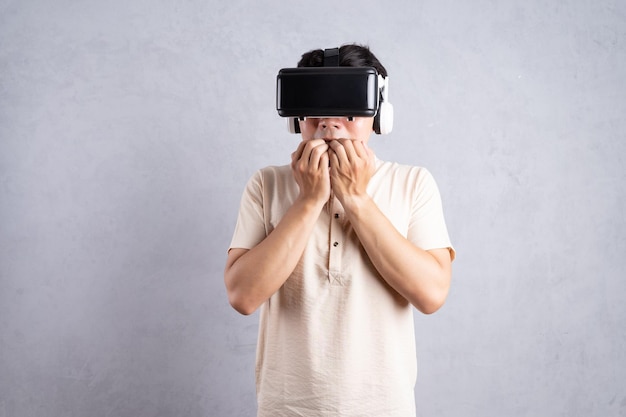 Young Asian man using VR glasses on background