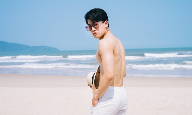 ビーチを歩くアジアの若い男