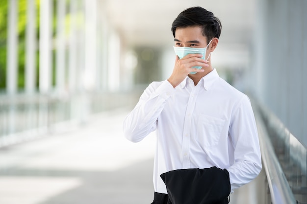 Il giovane uomo asiatico indossa una maschera medica per la protezione del coronavirus, covid-19 e pm2.5 in città urbana