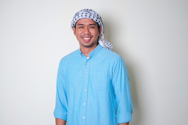 Young Asian man wearing Arabian Shemagh head scarf smiling friendly