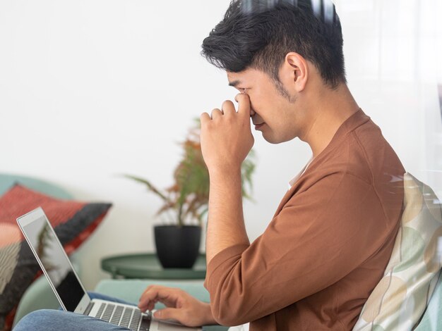 Young Asian man wearing casual clothes and having a headache