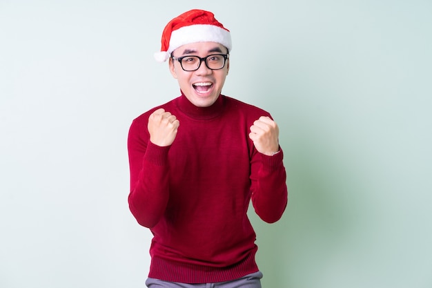 Young Asian man wearing christmas hat on green background