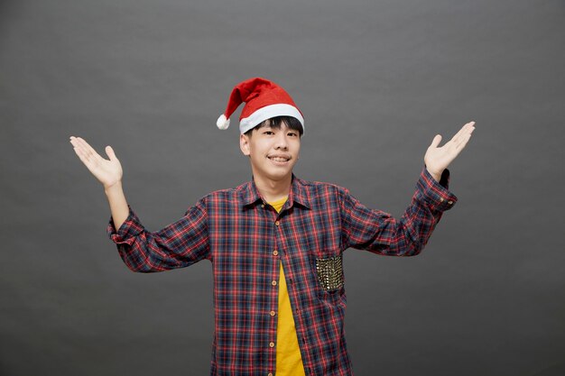 Молодой азиатский мужчина в новогодней шапке на студии выстрел, изолированный на сером фоне