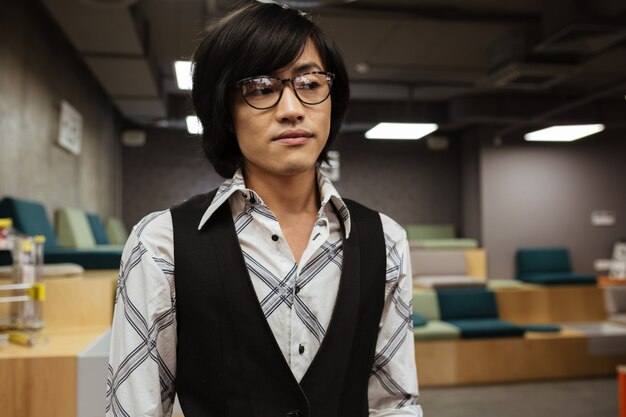 Young asian man wearing glasses looking aside.