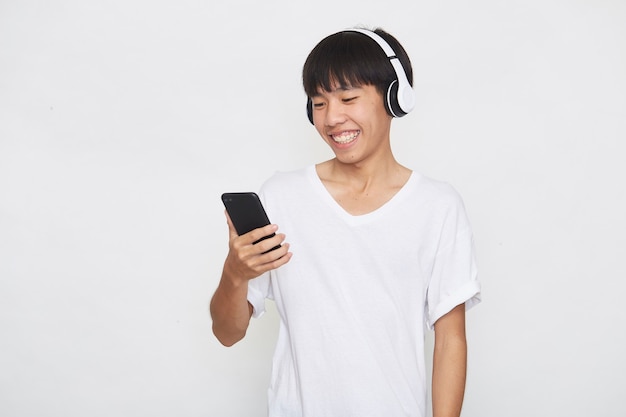 Young Asian man wearing headphones from a smartphone on white