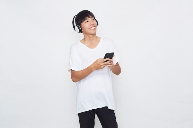 Young Asian man wearing headphones from a smartphone on white