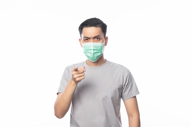 Young Asian Man wearing hygienic mask and pointing to camera with doubts face, 2019-nCoV or coronavirus. Airborne respiratory illness such as pm 2.5 fighting and flu isolated 