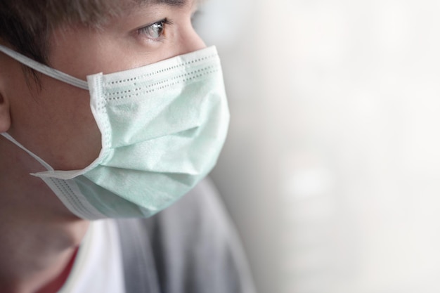 흰색 바탕에 의료용 얼굴 마스크를 쓴 젊은 아시아 남자. 개념 코로나바이러스, 대기 오염
