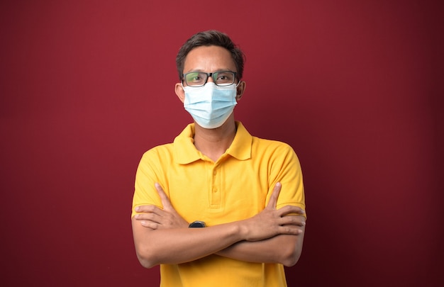 Young Asian Man wearing medical mask with crossed arms looking at the camera Positive person