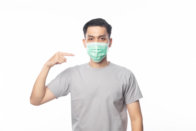 Young Asian Man wearing and pointing to hygienic mask to prevent infection