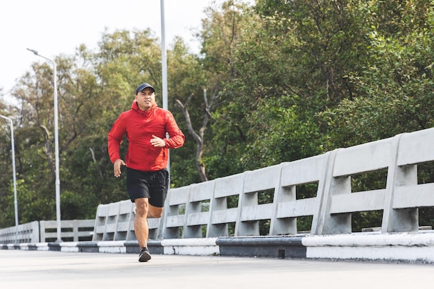 屋外で走っているスポーツウェアを着ている若いアジア人男性。道路でジョギングしているインド人の肖像画。アスリートアウトドアコンセプトのトレーニング。