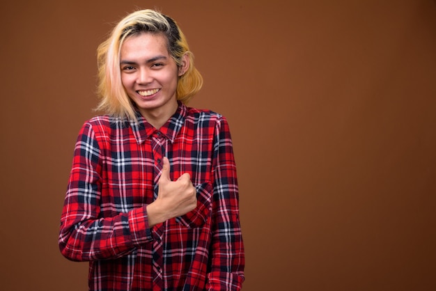 Young Asian man wearing stylish clothes against brown background