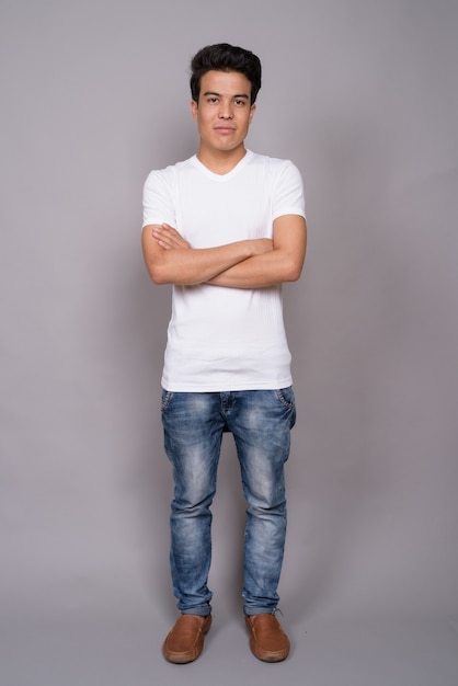 young Asian man wearing white shirt against gray wall