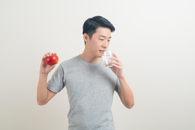 물과 사과 한 잔을 들고 있는 젊은 아시아 남자 - 건강한 개념