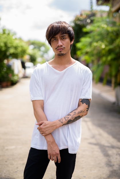 Young Asian man with hand tattoos in the streets outdoors