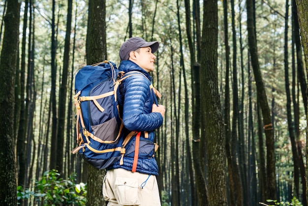 Young asian man with hat and backpack hiking