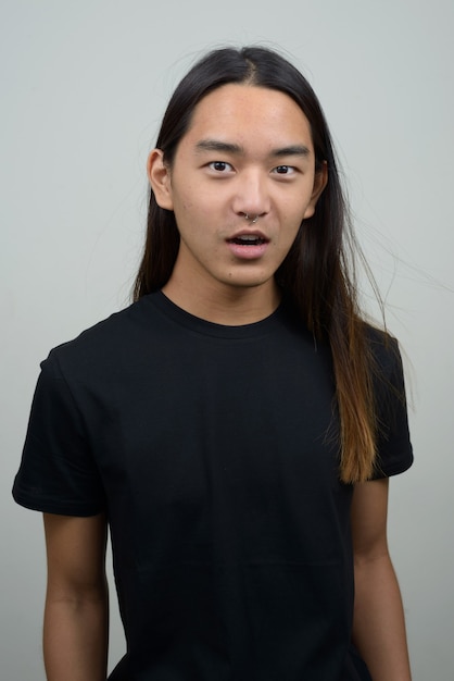 Young Asian man with long hair looking shocked