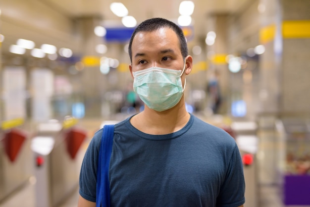 Giovane asiatico con maschera per la protezione dall'epidemia di coronavirus alla stazione della metropolitana