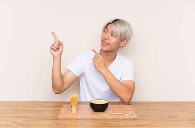 人差し指で素晴らしいアイデアを指しているテーブルで抹茶と若いアジア人