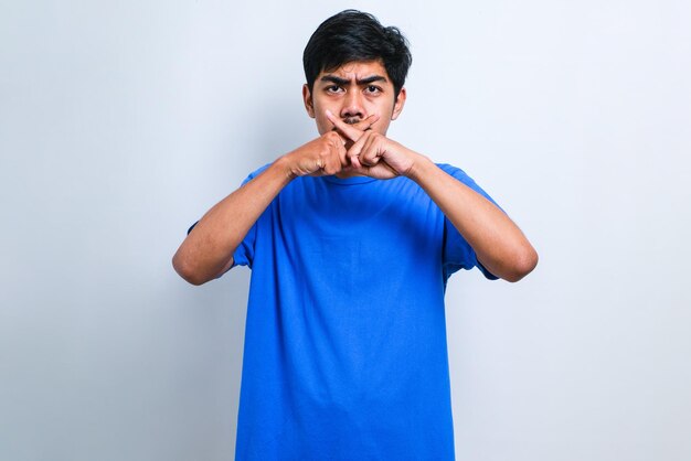 Young asian man with mustache wearing casual shirt rejection expression crossing fingers doing negative sign over white background