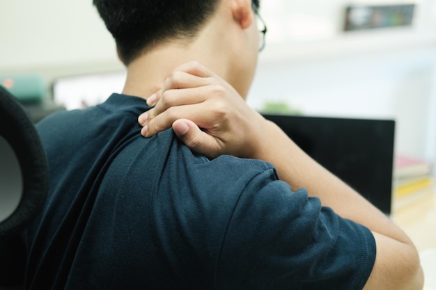 Young asian man with office syndrome have problem with part of body arm shoulder head neck back