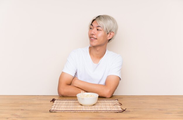 Young asian man with ramen in a table laughing