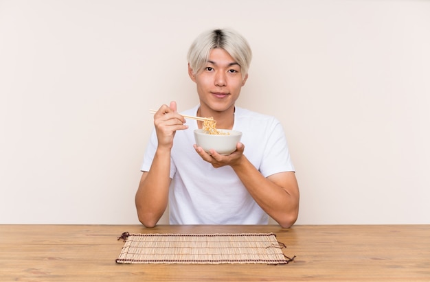 テーブルのラーメンと若いアジア人