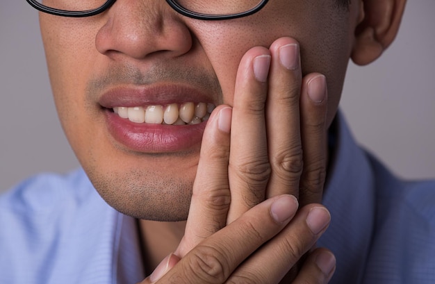 Giovane uomo asiatico con denti sensibili o mal di denti. sanità e concetto medico.