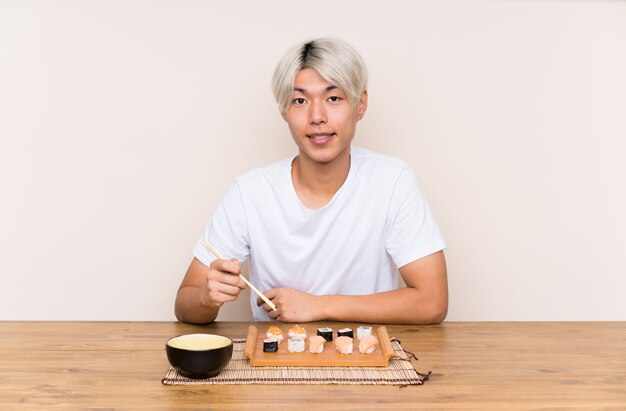 Young asian man with sushi in a table