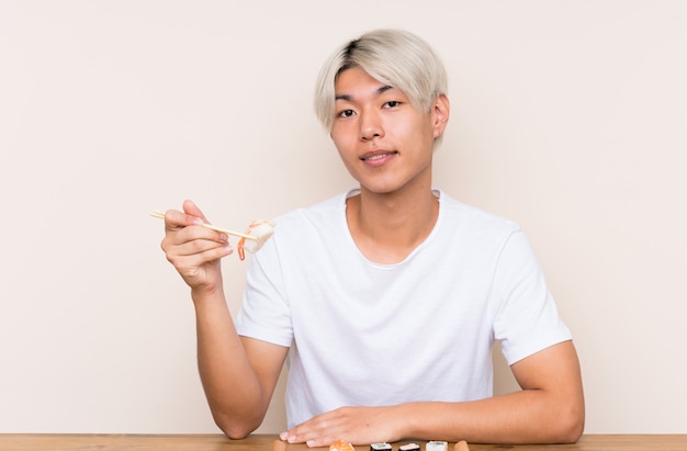 Young asian man with sushi in a table