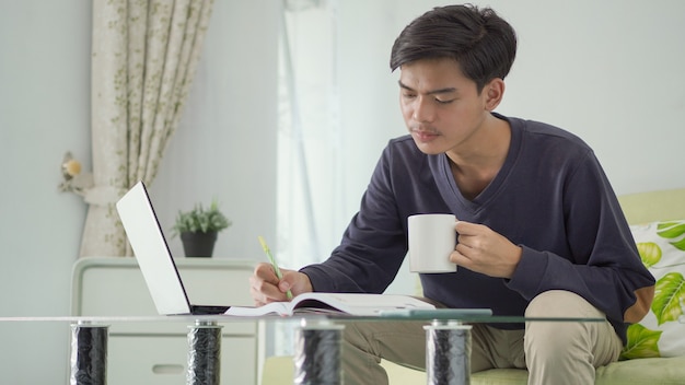 Young asian man working from home taking notes