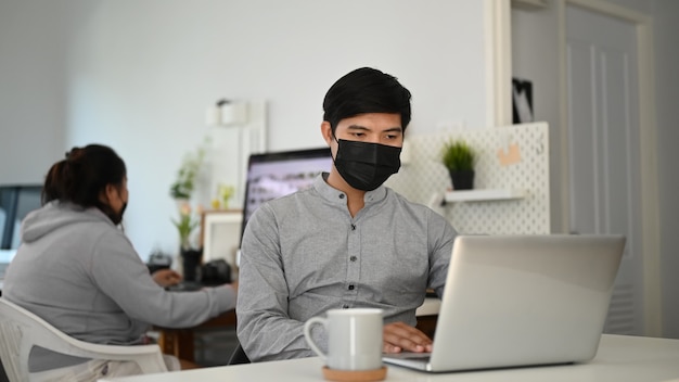 Young Asian man working on a laptop at his desk