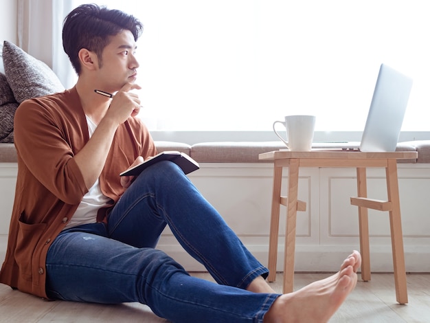 Young Asian man writing in a book