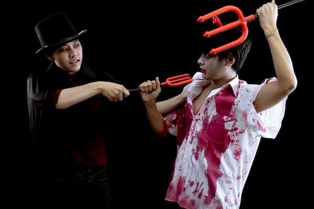 Young Asian men in costume hell, evil and wizard with fight on black background with concept for Halloween fashion festival in studio. Two teen Asian man in cosplay Halloween.