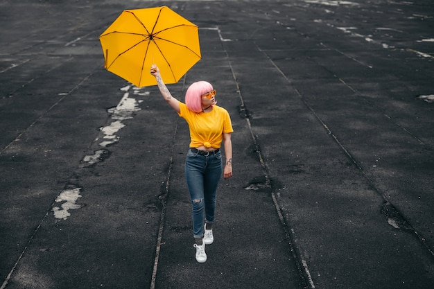 Photo young asian millennial hipster in stylish outfit carrying yellow umbrella