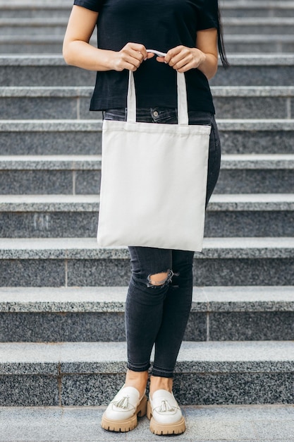 Young asian model girl dressed in a white tshirt on the street holding white eco bag mock up