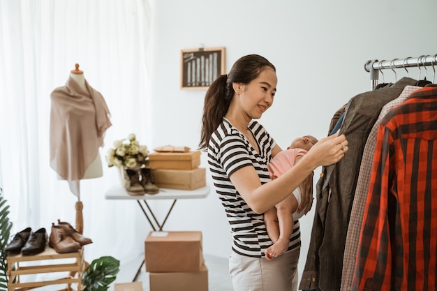 彼女の赤ん坊の娘と一緒に買い物に若いアジアのお母さん