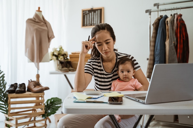 Young asian mom working from home with her daughter