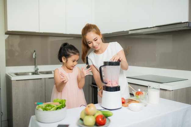 Young Asian mother and daughter making freshly squeezed tomato smoothies daughter is very happy