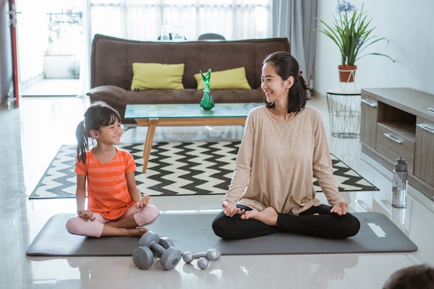 Giovane madre asiatica che fa esercizio di yoga a casa con sua figlia insieme