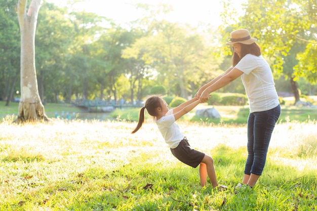 Young asian mother and little daughter playing the park