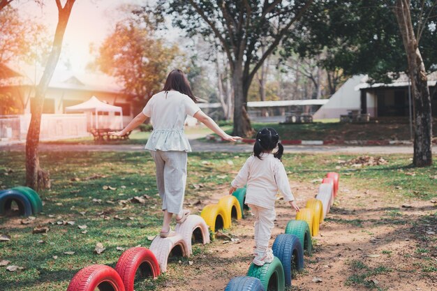 写真 遊び場で赤ちゃんと遊ぶ若いアジア人の母親ママと娘