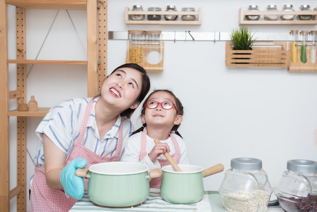 Young asian mother teaching her daughter how to cook