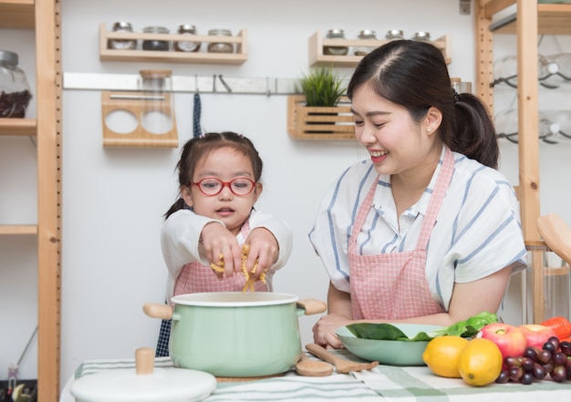 사진 요리하는 방법 그녀의 딸을 가르치는 젊은 아시아 어머니