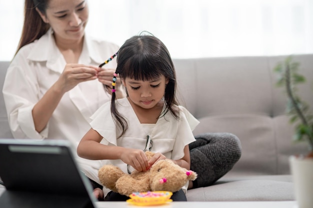 Young Asian mother tying daughter's hair