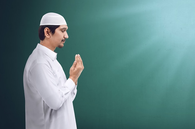 Young asian muslim man praying to god, muslim dress and wear caps