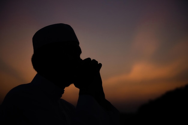 Un giovane uomo musulmano asiatico che prega sul concetto di festival del tramonto ramadan